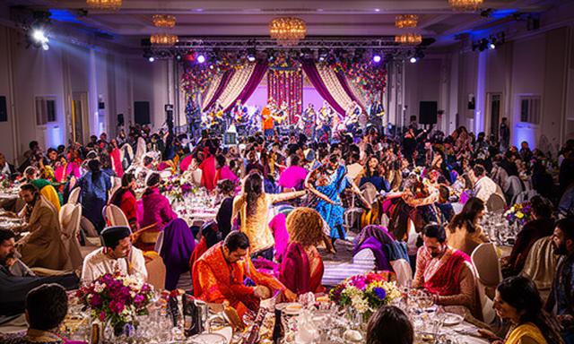 Grand Indian wedding reception in Berkshire with round guest tables and a live band